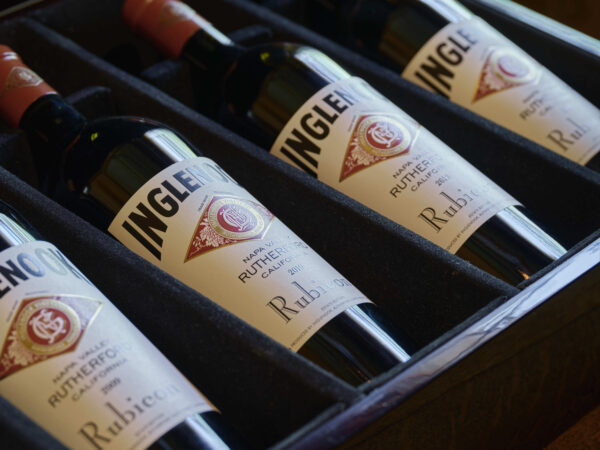 four bottles of wine zoomed in to enhance labels and visible laying in a dark wooden box